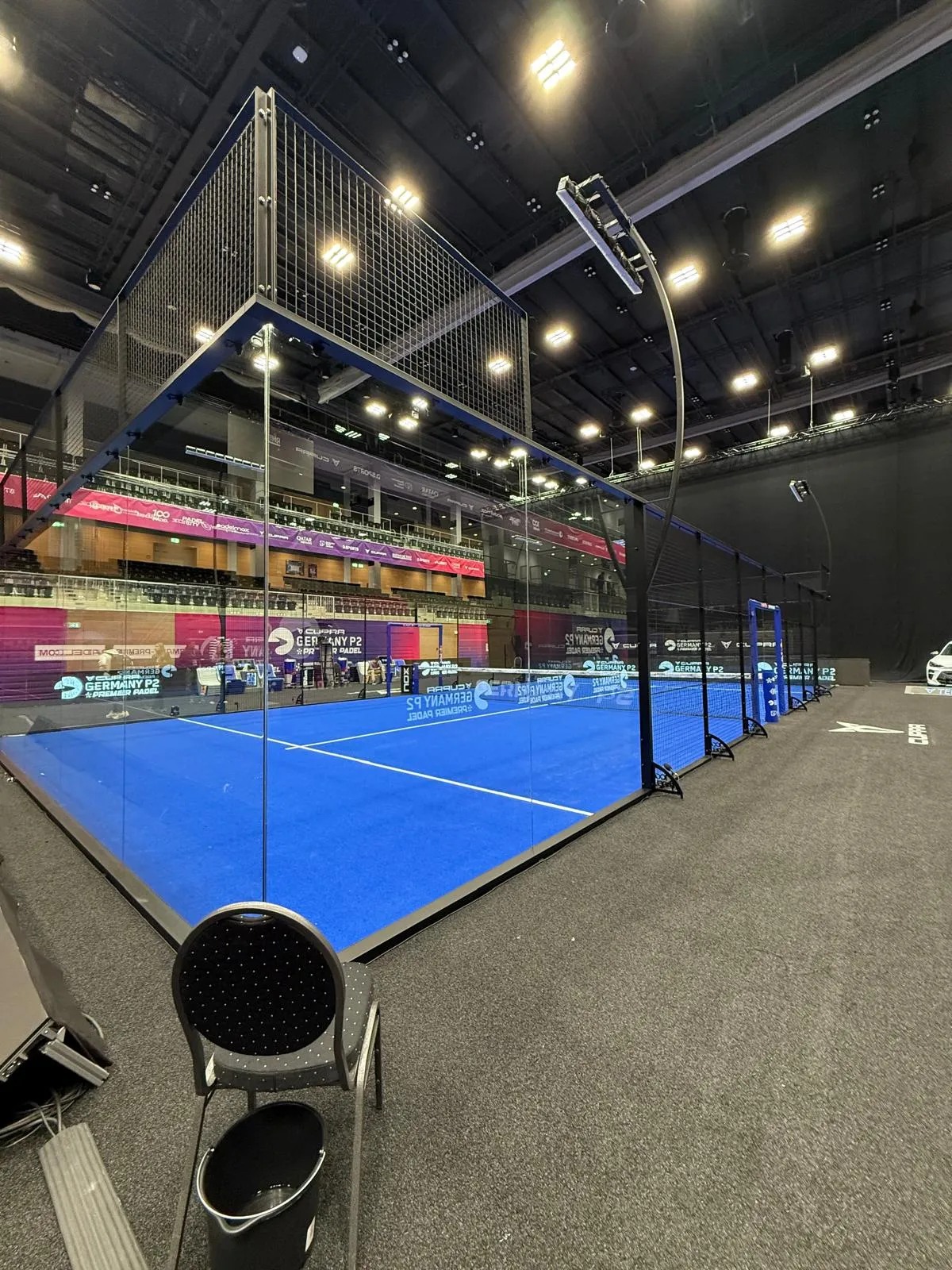 Pista de pádel azul profesional con barreras de cristal y señalización