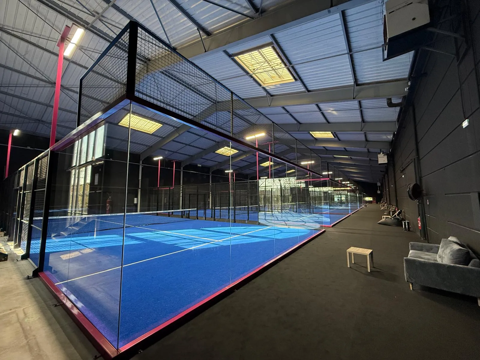 Pista de pádel indoor con superficie azul y estructura profesional